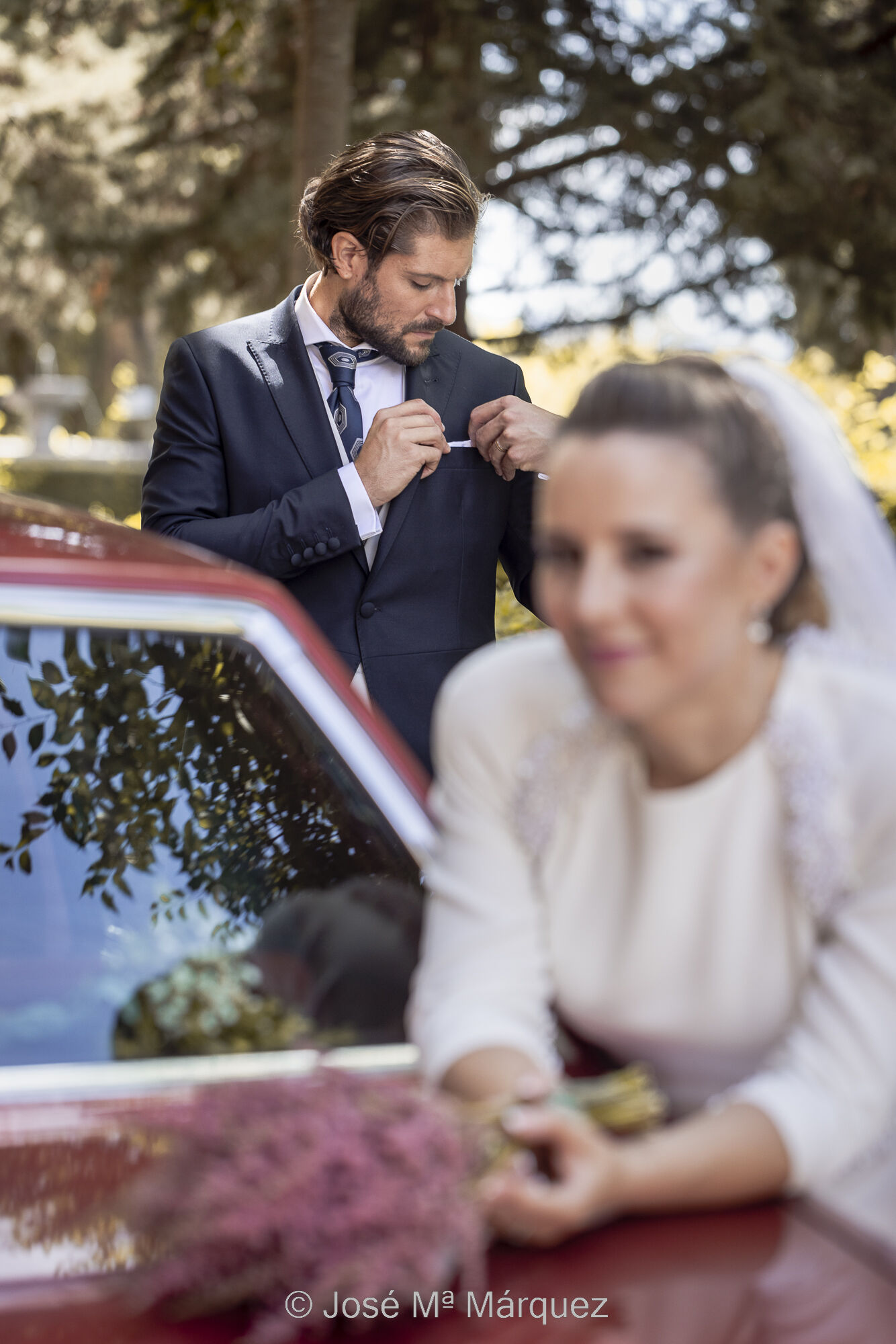 José María Márquez. Fotógrafo de Granada. - reportaje-boda-exteriores-la-desenfocada-apoyada-en-el-coche-el-novio-al-fondo-se-arregla-el-panuelo-fotografos-boda-granada.jpg