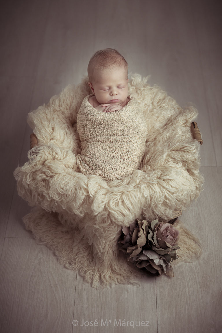 Sesión new born en estudio. Bebé recién nacida envuelta en wrap y sobre flokati de lana a juego. Fotógrafo de Bebés recién nacidos en Granada.