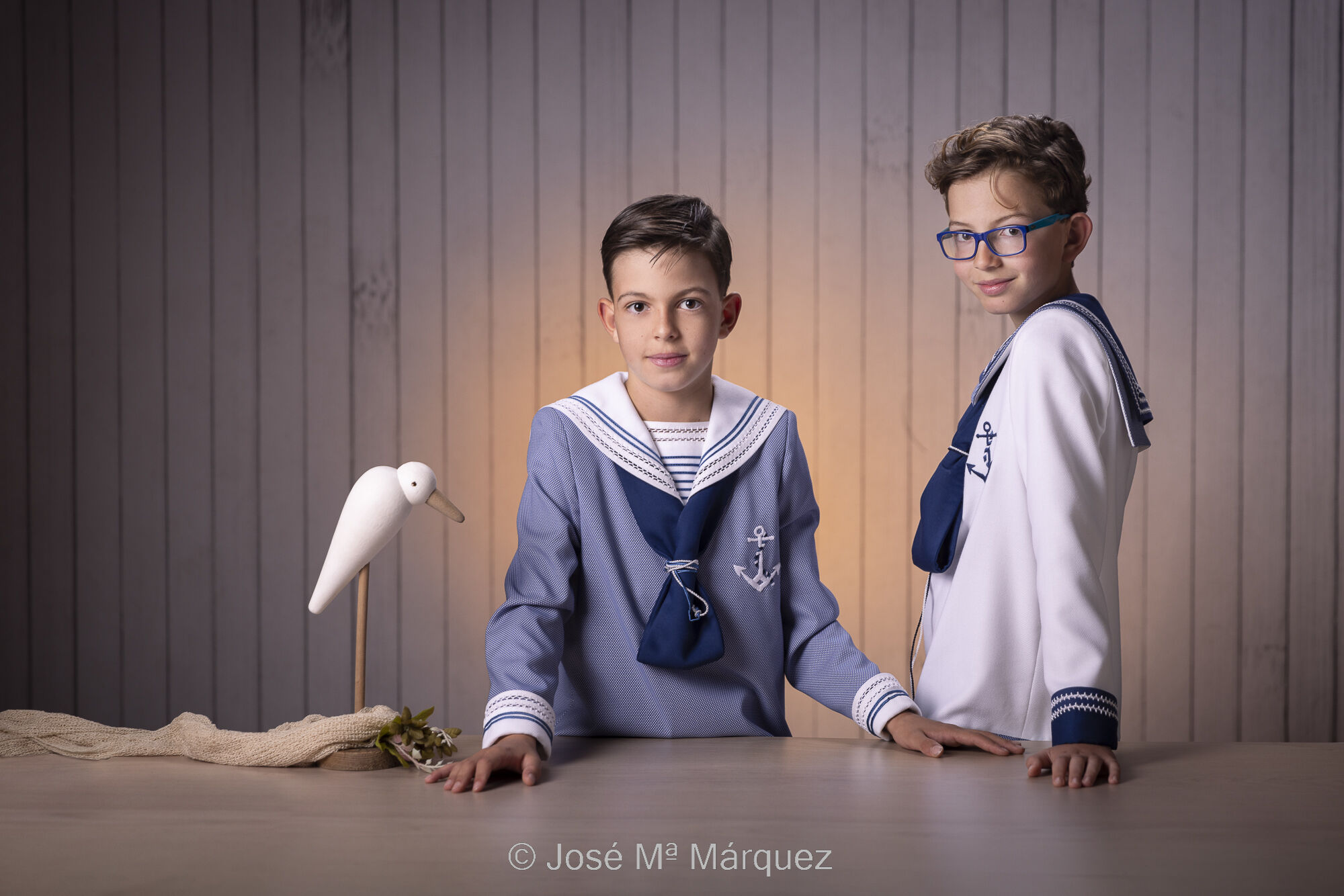 José María Márquez. Fotógrafo de Granada. - fotografia-de-primera-comunion-sesion-de-estudio-de-dos-hermanos-apoyados-en-una-mesa-con-una-gaviota-fotografo-comuniones-de-granada.jpg