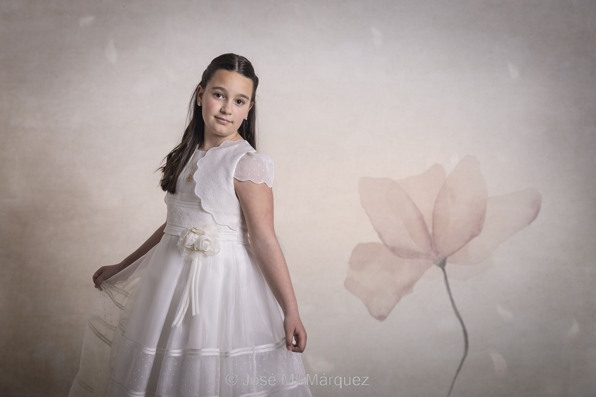 José María Márquez. Fotógrafo de Granada.  - sesion-de-estudio-de-una-nina-de-comunion-foto-con-una-flor-en-el-fondo-la-nina-se-sujeta-el-vestido-gracilmente-fotografo-primeras-comuniones.jpg