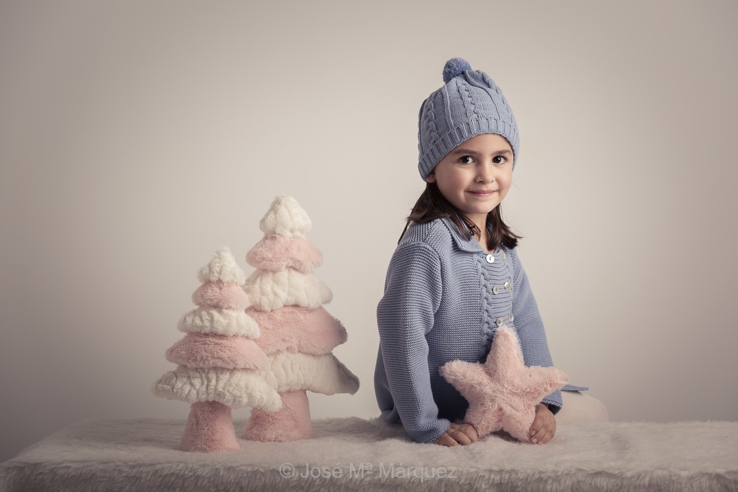 Fotografía niña ropa de invierno para Sesión de Estudio con decorado de pinos y estrella de Navidad. Fotógrafo en Granada