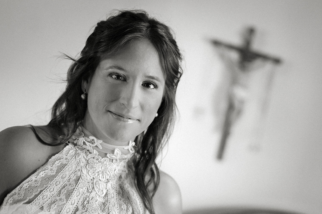 Plano corto de la novia en su casa. Crucifijo de pared al fondo..