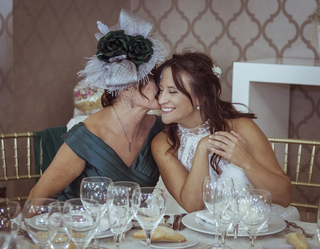 La madre da un beso a la novia durante la celebración en La Mamunia. Instantánea de Boda.