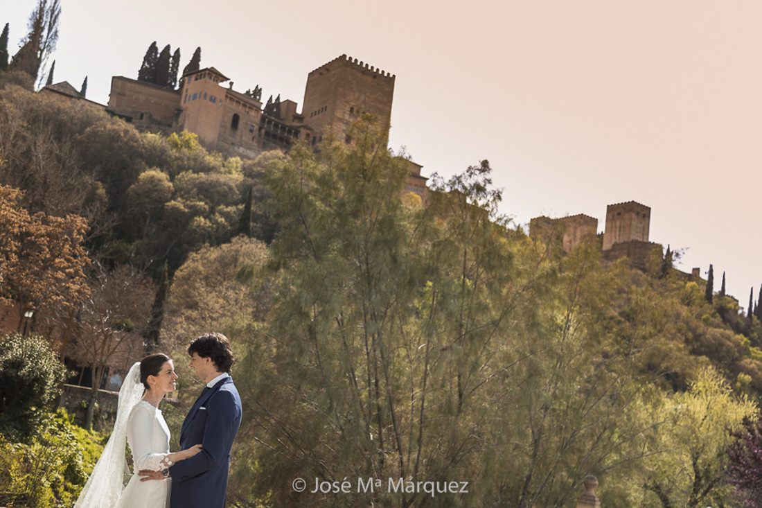 Reportaje de boda en exteriores. Pareja en Granada. Foto en el Paseo de los Tristes, con la Alhambra al fondo.