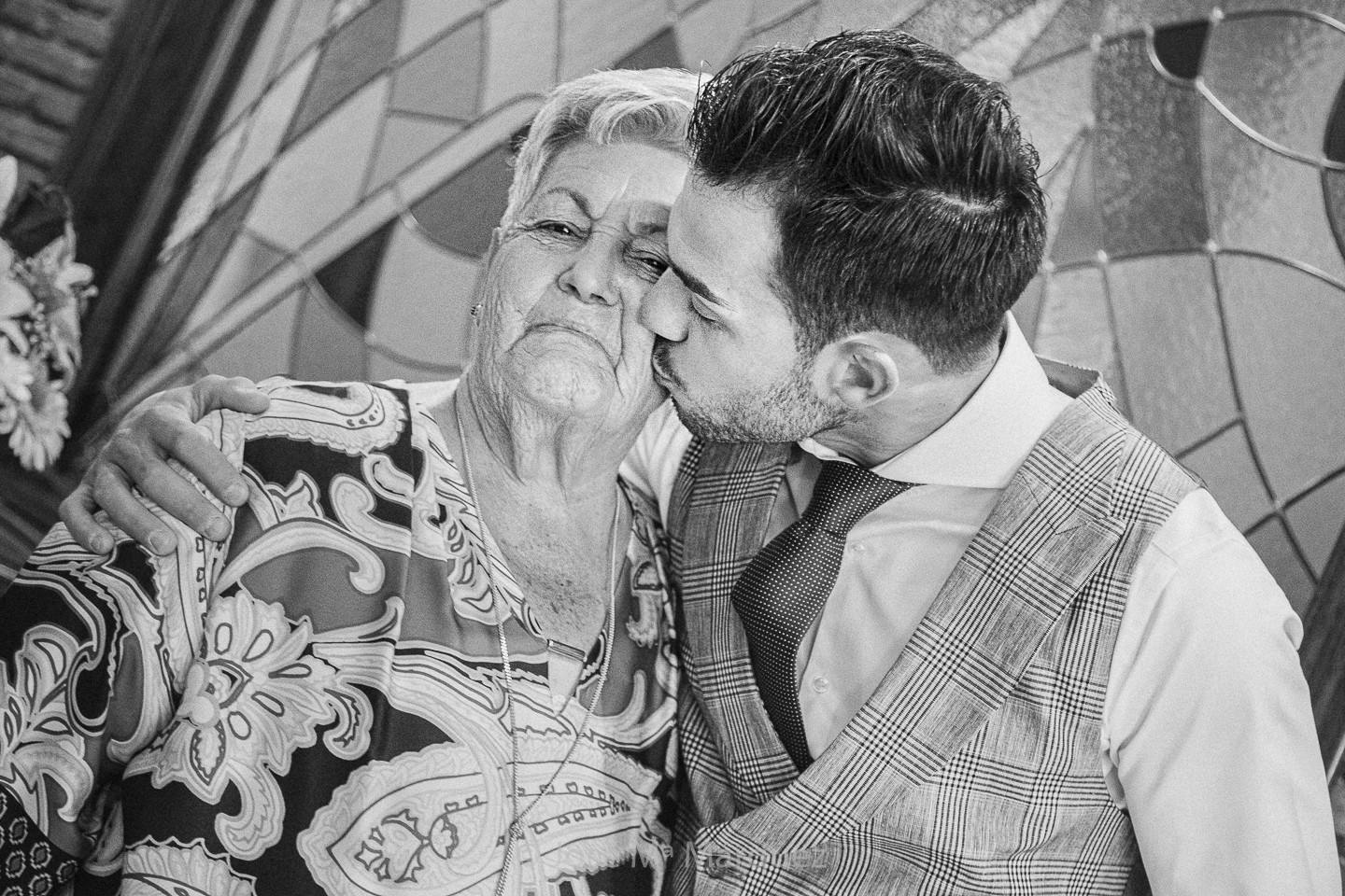 La abuela del novio hace un puchero cuando éste le abraza y le besa. Fotografía instantánea de fotógrafos de boda en Granada. 
