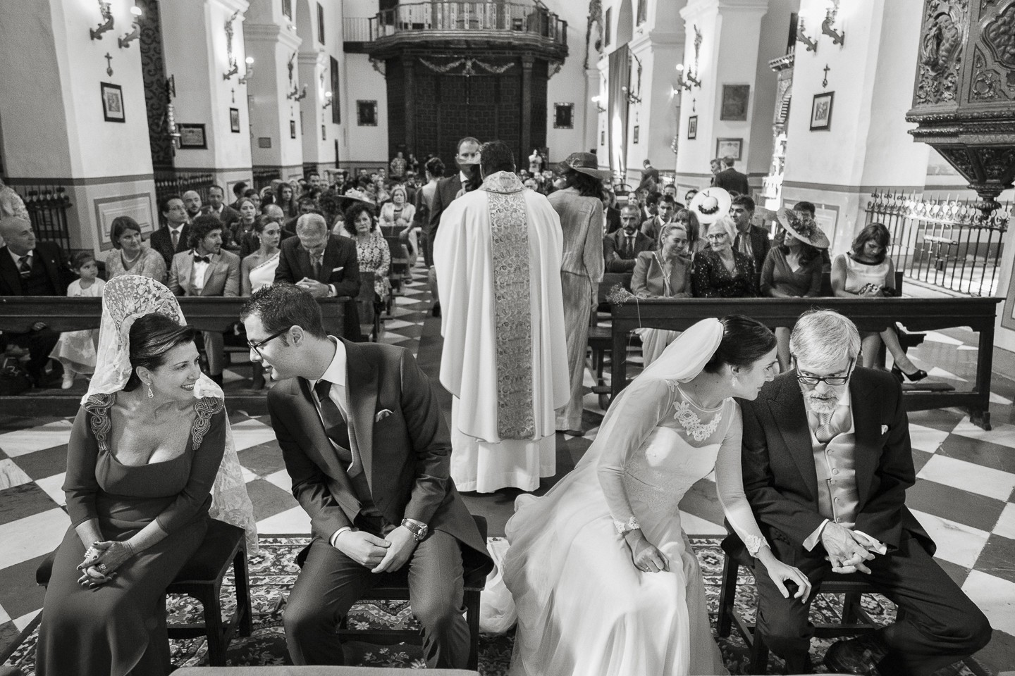 Reportaje de Boda en la Iglesia de Santa Ana. Los novios se acercan a sus respectivos padres para comentar mientras el sacerdote da la Comunión. Fotógrafos de Granada.