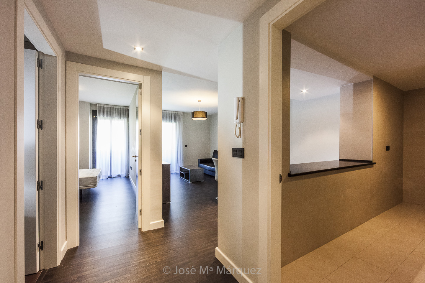 Cocina americana, salón y dormitorio de un apartamento amueblado en venta con suelos de madera. Fotografía de Interiorismo
