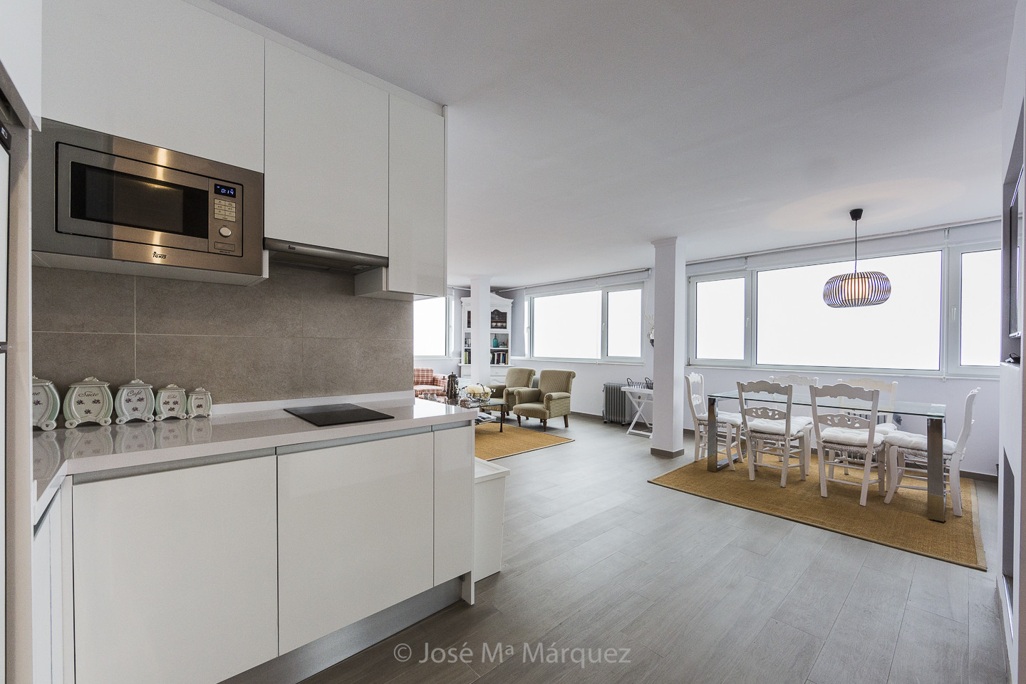 Salón con dos ambientes, cocina integrada y grandes ventanales de un apartamento en alquiler en S. Nevada. Fotografía profesional